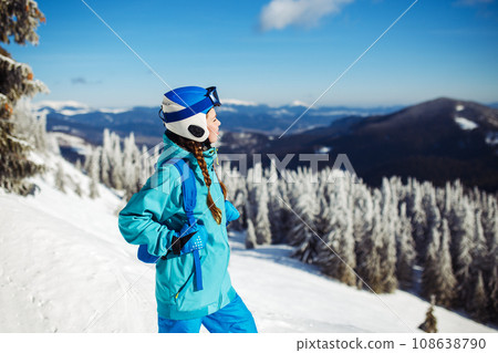 Girl in winter clothes drinking tea on the background of snow-capped mountains on the sunny day. Girl in winter clothes drinking tea on the background of snow-capped mountains on the sunny day. 108638790