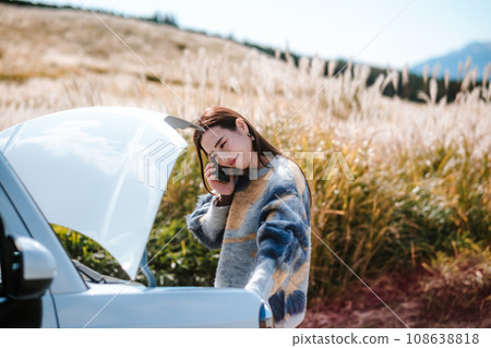 A woman is in trouble because her car broke down while driving. 108638818
