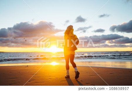 Tourist in yellow jacket enjoying sea landscape at sunset. Lifestyle, travel, nature, active life. Tourist in yellow jacket enjoying sea landscape at sunset. Lifestyle, travel, nature, active life. 108638937