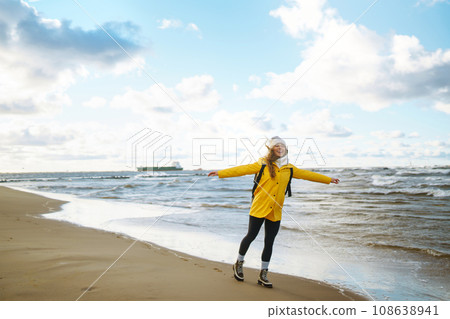 The girl tourist in a yellow jacket posing by the sea. Travelling, lifestyle, adventure. The girl tourist in a yellow jacket posing by the sea. Travelling, lifestyle, adventure. 108638941