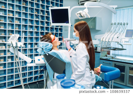 Young woman at the dentist's chair during a dental procedure. Overview of dental caries prevention. 108639337