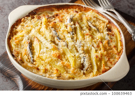 Jansson's frestelse or Janssons temptation is a Swedish gratin style dish made from potatoes, onion and sprats closeup on the baking dish. Horizontal 108639463