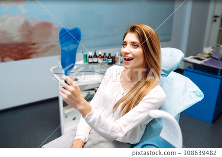 Young woman at the dentist's chair during a dental procedure. Overview of dental caries prevention. 108639482