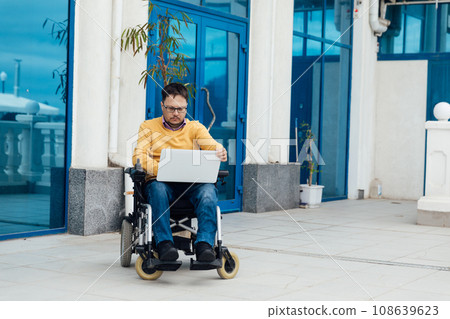 a special person with disabilities with a laptop talking on the phone 108639623