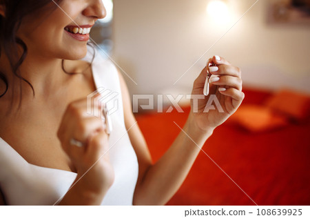 Morning of the bride. Beautiful smiling brunette bride in a white dress with a wedding bouquet in her hands. Morning of the bride. Beautiful smiling brunette bride in a white dress with a wedding bouquet in her hands. 108639925