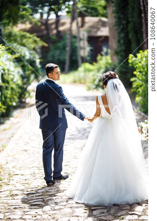 The bride and groom walk together in the park. Pretty bride and stylish groom. Wedding day. Marriage. 108640067