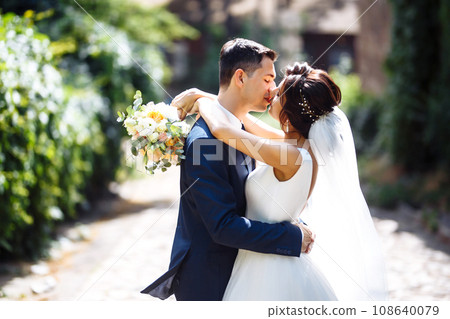 The bride and groom walk together in the park. Pretty bride and stylish groom. Wedding day. Marriage. 108640079