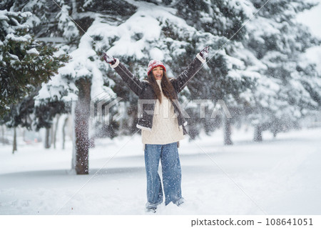 Beautiful woman standing among snowy trees and enjoying first snow. Holidays, rest, travel concept. Beautiful woman standing among snowy trees and enjoying first snow. Holidays, rest, travel concept. 108641051