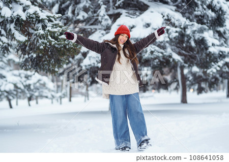 Beautiful woman standing among snowy trees and enjoying first snow. Holidays, rest, travel concept. Beautiful woman standing among snowy trees and enjoying first snow. Holidays, rest, travel concept. 108641058