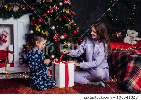 Mom with son at christmas tree with gifts new garland winter 108641828