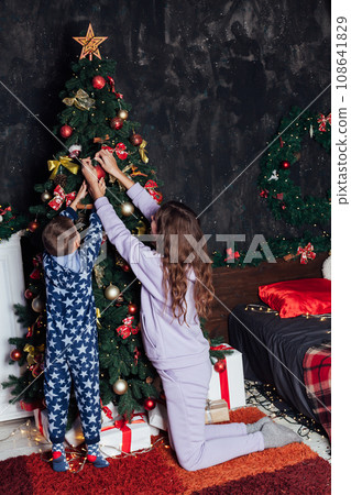 Mom with son at christmas tree with gifts garland winter Mom with son at christmas tree with gifts garland winter 108641829