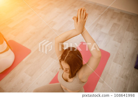 Girl does yoga. Young woman practices asanas on a beige one-ton background. Girl does yoga. Young woman practices asanas on a beige one-ton background. 108641998