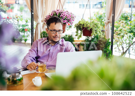 a man works in a restaurant remotely with a laptop a man works in a restaurant remotely with a laptop 108642522