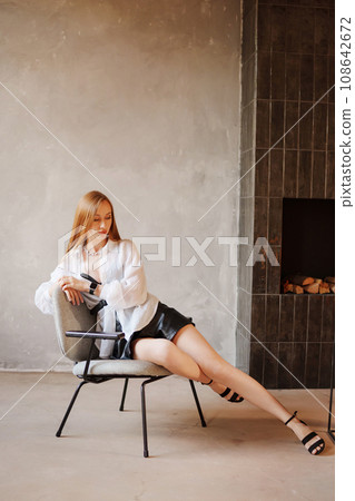 Portrait of sexy redhead young woman in white shirt on a chair. Portrait of sexy redhead young woman in white shirt on a chair. 108642672