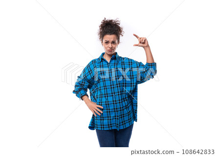 a young woman with a careless curly hairstyle dressed in a casual shirt shows the size of an object a young woman with a careless curly hairstyle dressed in a casual shirt shows the size of an object 108642833