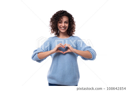 a kind young woman with black curly hair dressed in a light blue sweater shows a heart with her 108642854