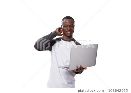 a young American man dressed in a black and white sweater happily works in IT. man holding laptop a young American man dressed in a black and white sweater happily works in IT. man holding laptop 108642955
