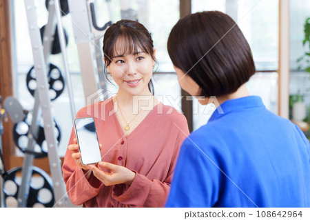顧客向健身房工作人員展示智慧型手機螢幕 顧客向健身房工作人員展示智慧型手機螢幕 108642964