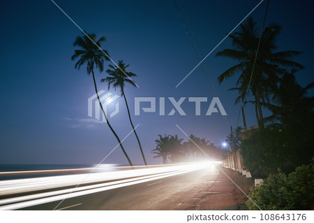 Light trail of car on coastal road at full Moon night 108643176