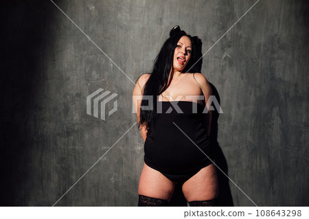 a fat woman in stockings stands on a black background 108643298