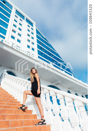 a woman stands on the stairs near a tall building a woman stands on the stairs near a tall building 108643320