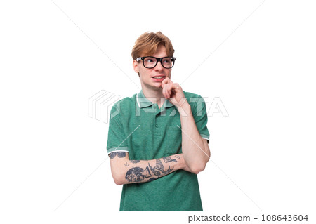 young red-haired man in a green t-shirt stands thoughtfully on a white background with copy space young red-haired man in a green t-shirt stands thoughtfully on a white background with copy space 108643604