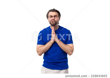 young brunette European man with a well-groomed beard in a blue T-shirt hopes for the best young brunette European man with a well-groomed beard in a blue T-shirt hopes for the best 108643605
