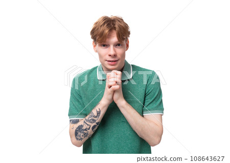 young handsome red-haired man dressed in a green t-shirt looks at the camera on the background with young handsome red-haired man dressed in a green t-shirt looks at the camera on the background with 108643627