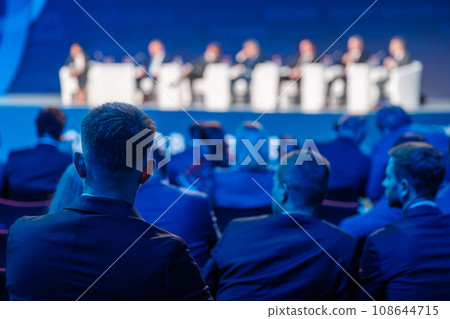 Business professionals listening to board of directors on stage during conference meeting at export forum  108644715