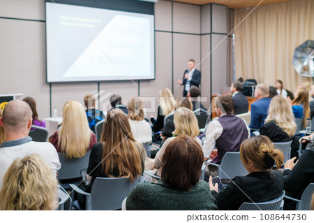 Back view of businesswoman attending presentation with diverse participants in conference hall Back view of businesswoman attending presentation with diverse participants in conference hall 108644730