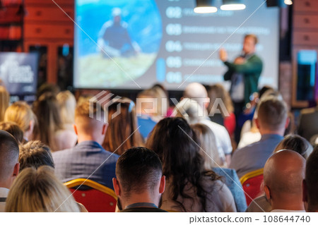 Back view of multiethnic business professionals listening to speaker giving presentation in conference hall 108644740
