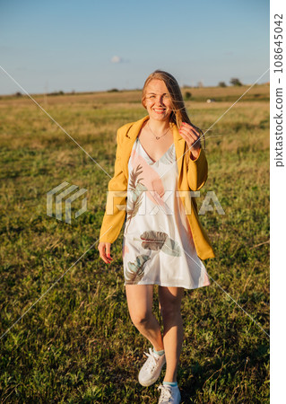 blonde woman in yellow clothes in nature green meadow 108645042