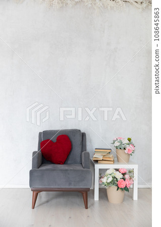 grey armchair with cushion with coffee table with books and flowers 108645863