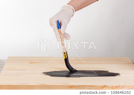 painting wooden background, hand with brush and can of paint 108646202