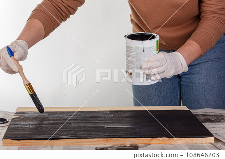 painting wooden background, hand with brush and can of paint 108646203