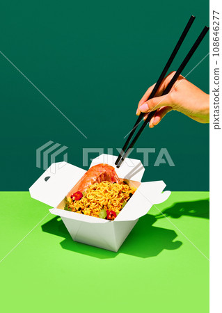 Unrecognizable people eating with chopstick tasty hot WOK with shrimps from paper box isolated green studio background Unrecognizable people eating with chopstick tasty hot WOK with shrimps from paper box isolated green studio background 108646277
