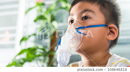Asian Child using nebulizer mask equipment alone have smoke, Kid boy making makes inhalation nebulizer steam sick cough at home, oxygen spray inhaler therapy, stuffy nose and runny, Health medical 108646818