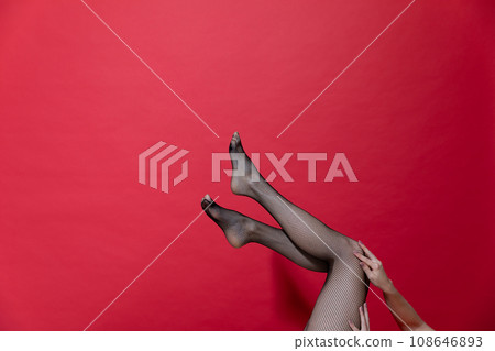 slender beautiful women's legs on a red background slender beautiful women's legs on a red background 108646893