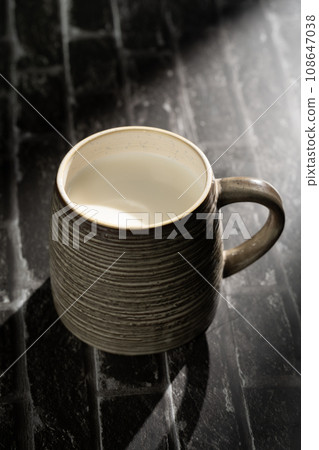 Sunlight shining on a slate board with a cup of milk. Sunlight shining on a slate board with a cup of milk. 108647038