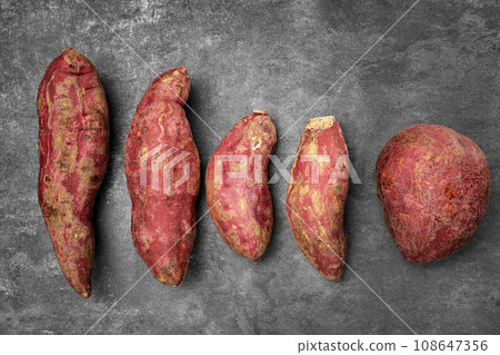 Old sweet potatoes placed on a black slate board. Old sweet potatoes placed on a black slate board. 108647356