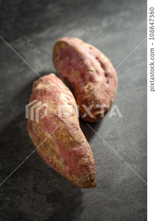 Old sweet potatoes placed on a black slate board. Old sweet potatoes placed on a black slate board. 108647360