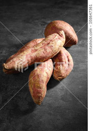 Old sweet potatoes placed on a black slate board. Old sweet potatoes placed on a black slate board. 108647361