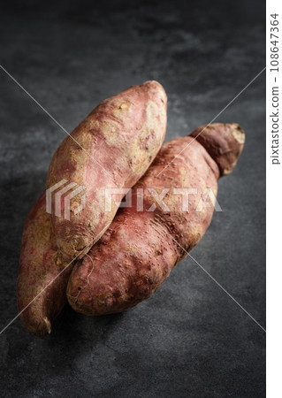 Old sweet potatoes placed on a black slate board. Old sweet potatoes placed on a black slate board. 108647364