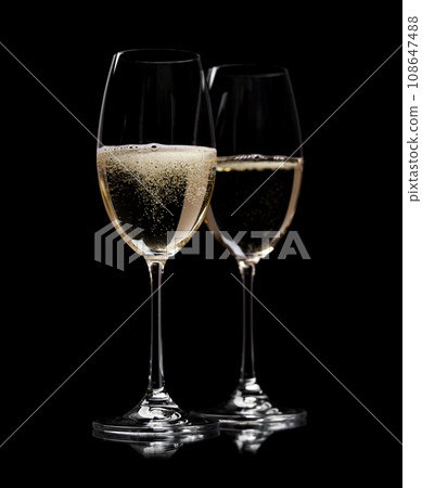 Two champagne glasses on a black 108647488
