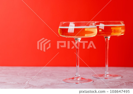 Two champagne glasses on a red 108647495