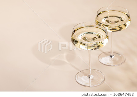 Two champagne glasses on a beige 108647498