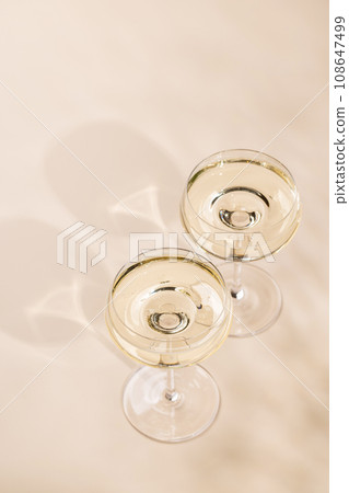Two champagne glasses on a beige 108647499
