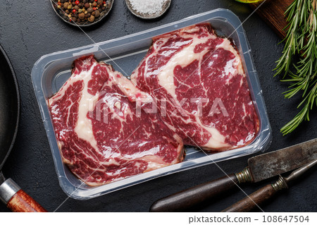 Raw ribeye steaks with savory spices 108647504