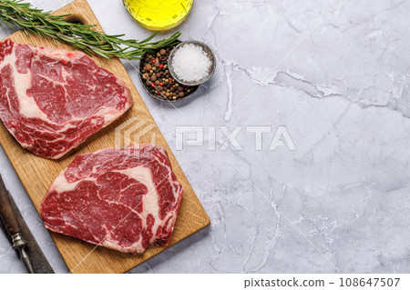 Raw ribeye steaks with savory spices 108647507