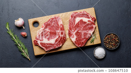 Raw ribeye steaks with savory spices 108647510